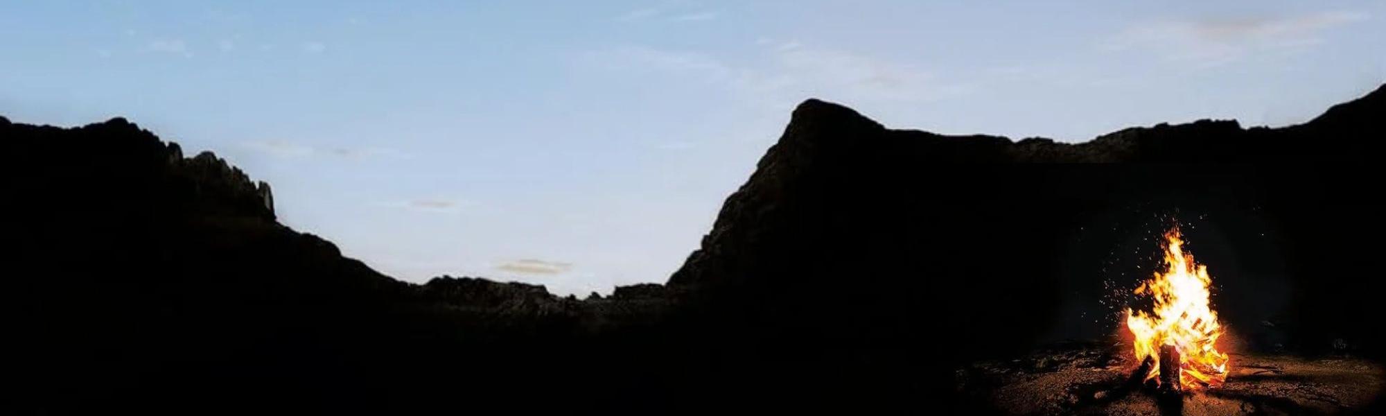Evening sky behind mountains with camp fire