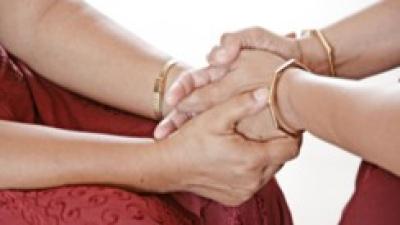 Two people holding hands in prayer